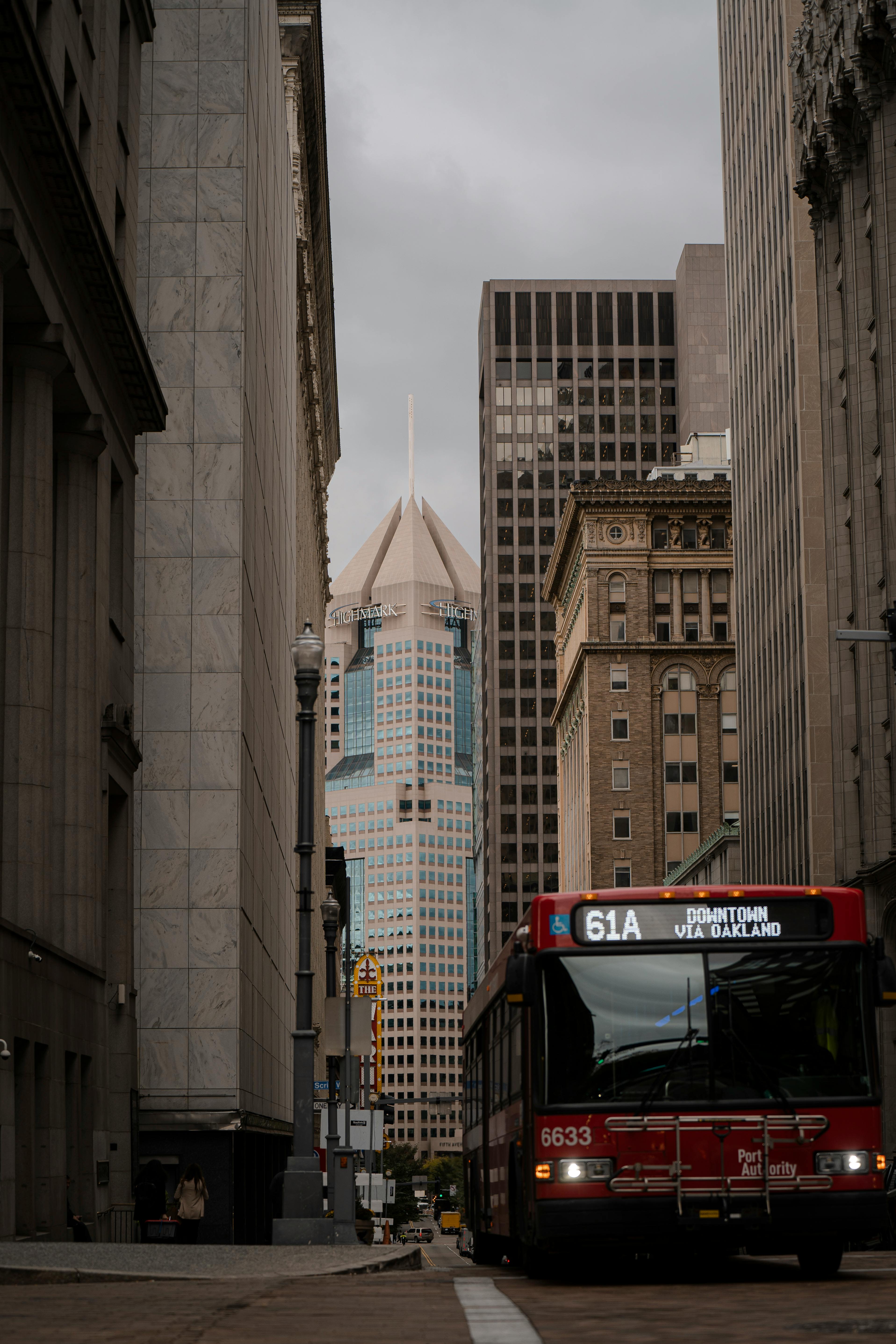 A city bus moves through downtown Pittsburgh with skyscrapers in the background.