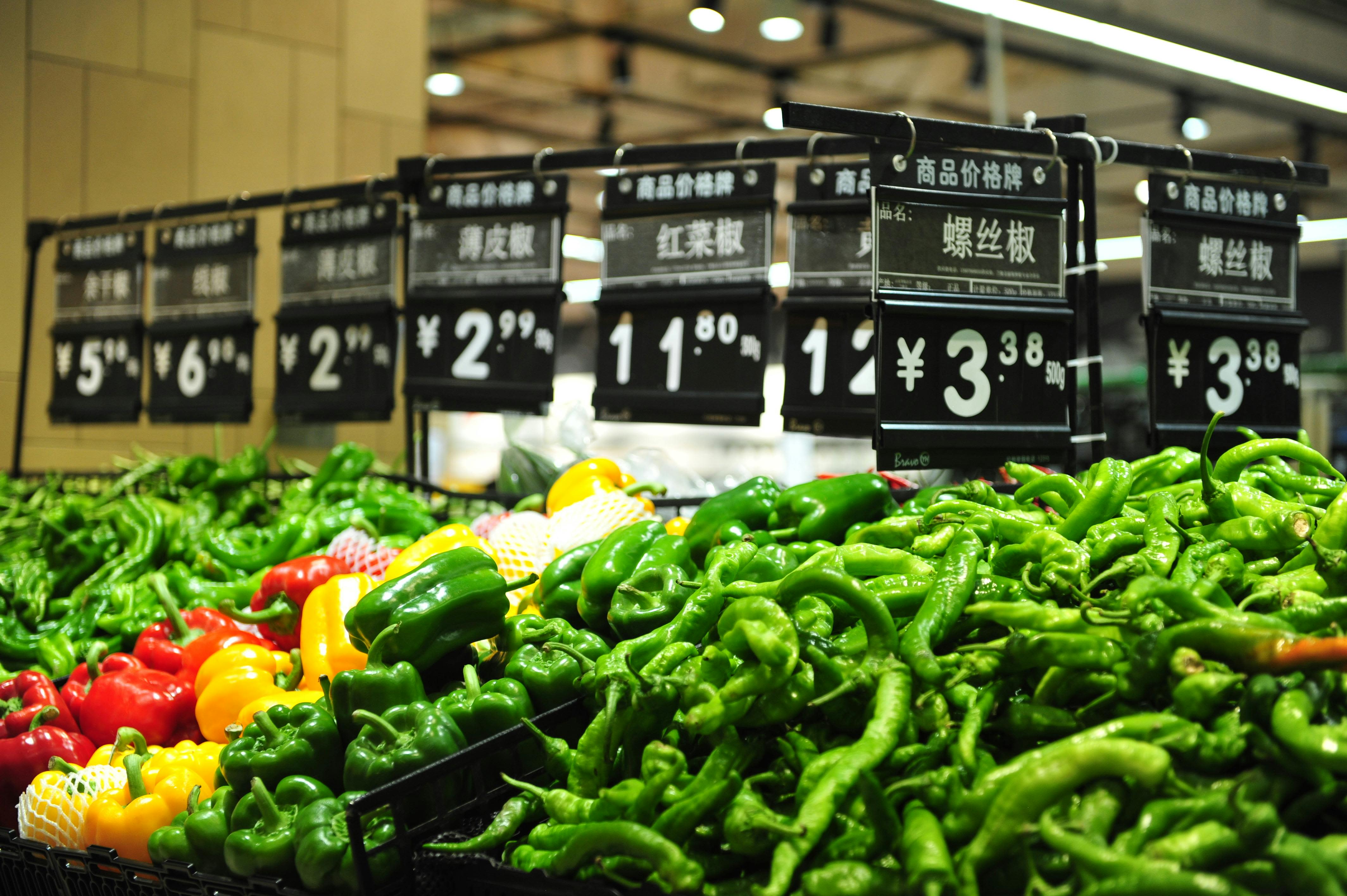 Vibrant bell peppers on display in a Chinese market with price tags.