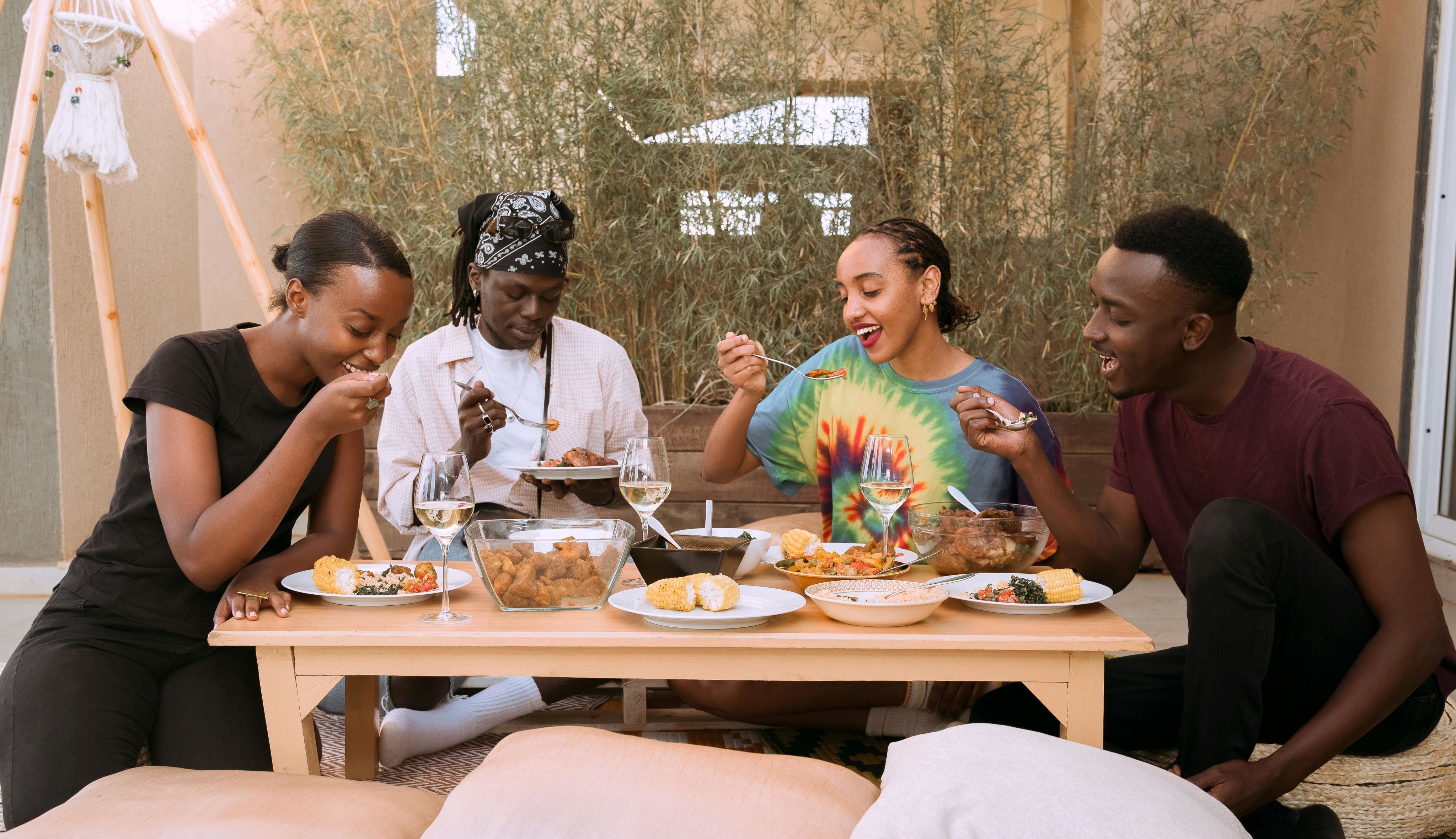 A joyful group of friends enjoying a meal together outdoors, showcasing diversity and friendship.