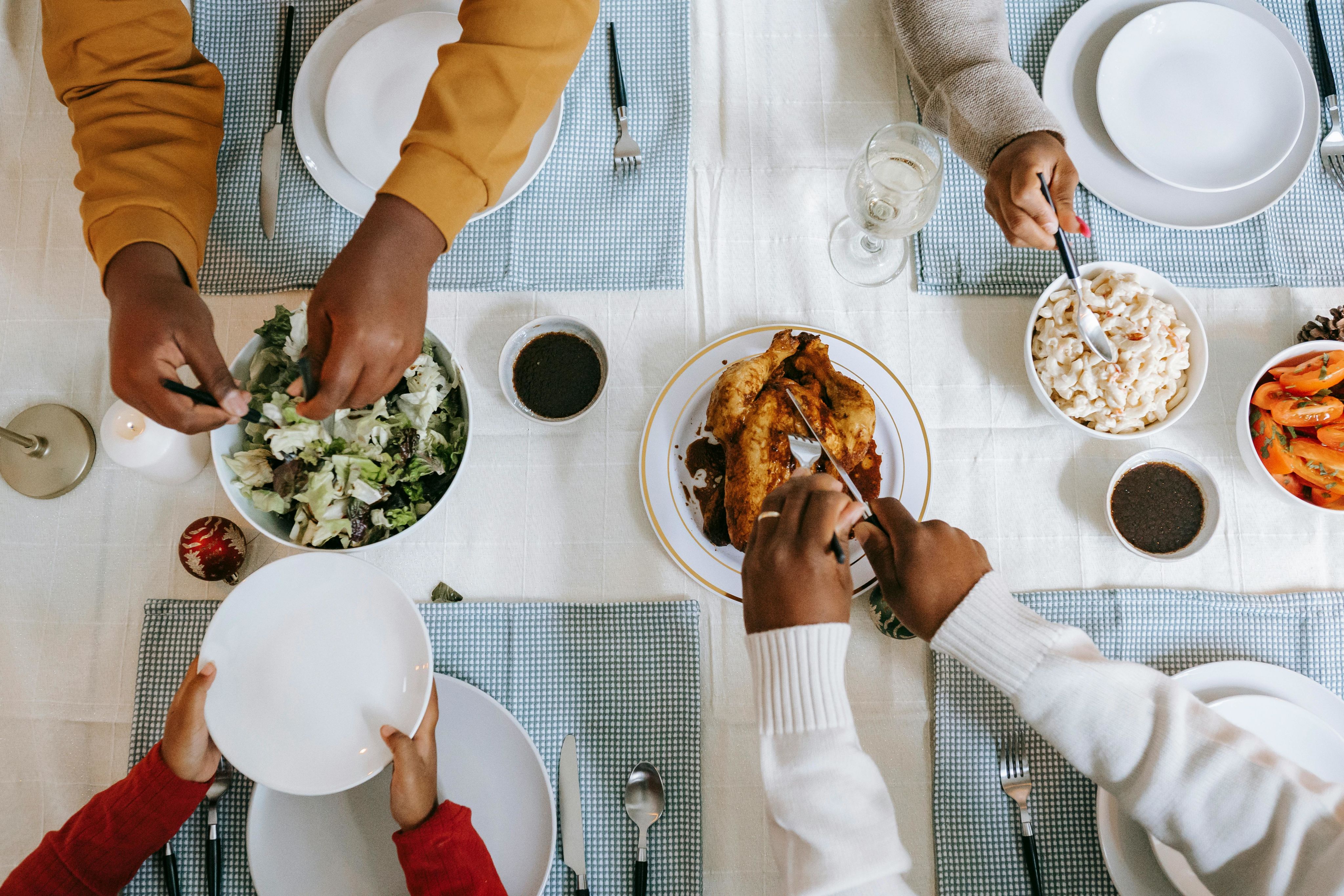 A diverse family enjoying a meal together, sharing dishes at a well-set table. - Photo by Any Lane on Pexels