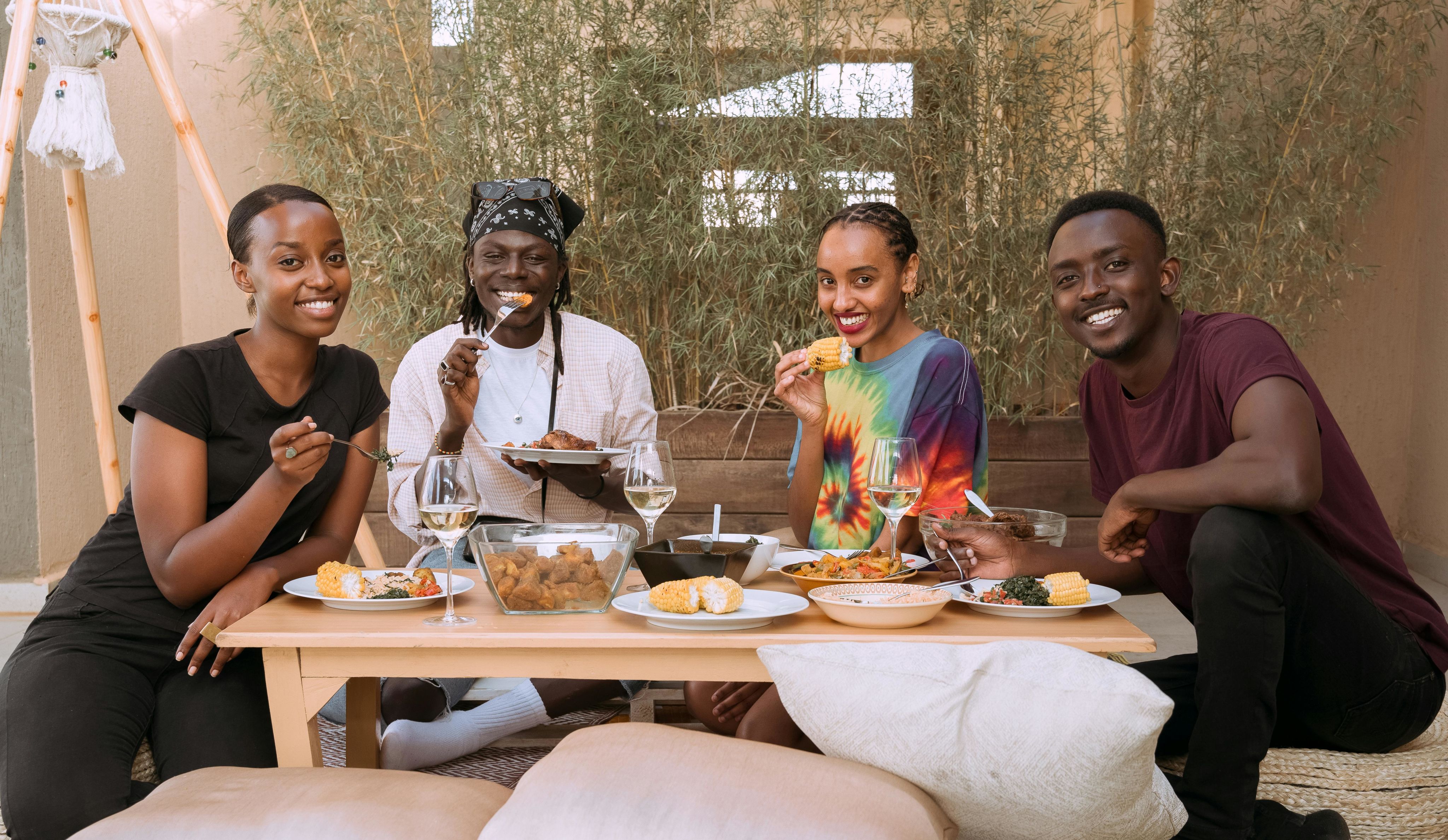 Four friends smiling and enjoying a meal together, exuding joy and togetherness. - Photo by PICHA on Pexels