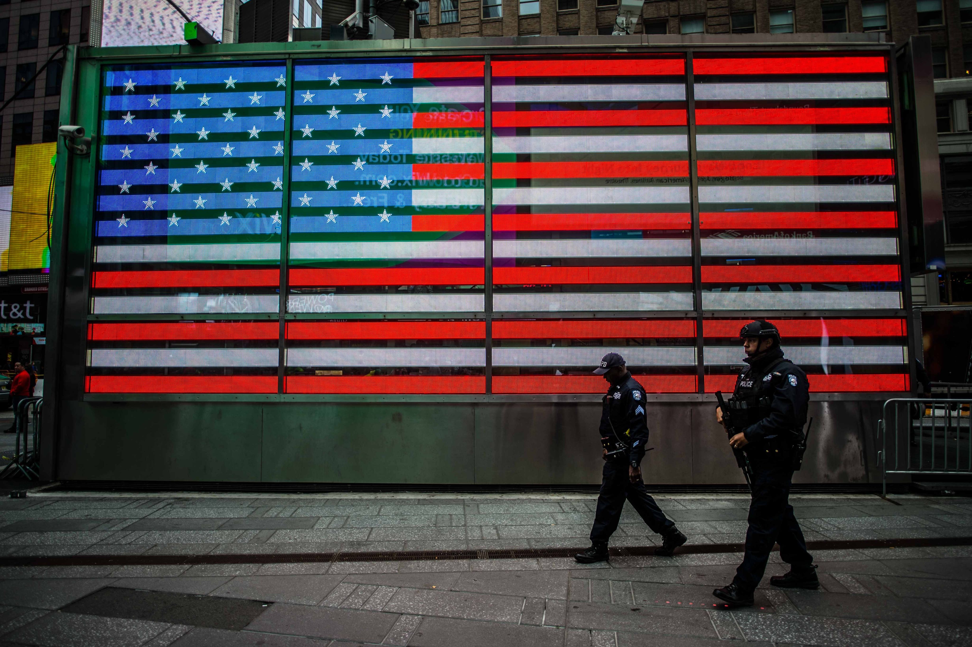 two man walks near USA flag wall