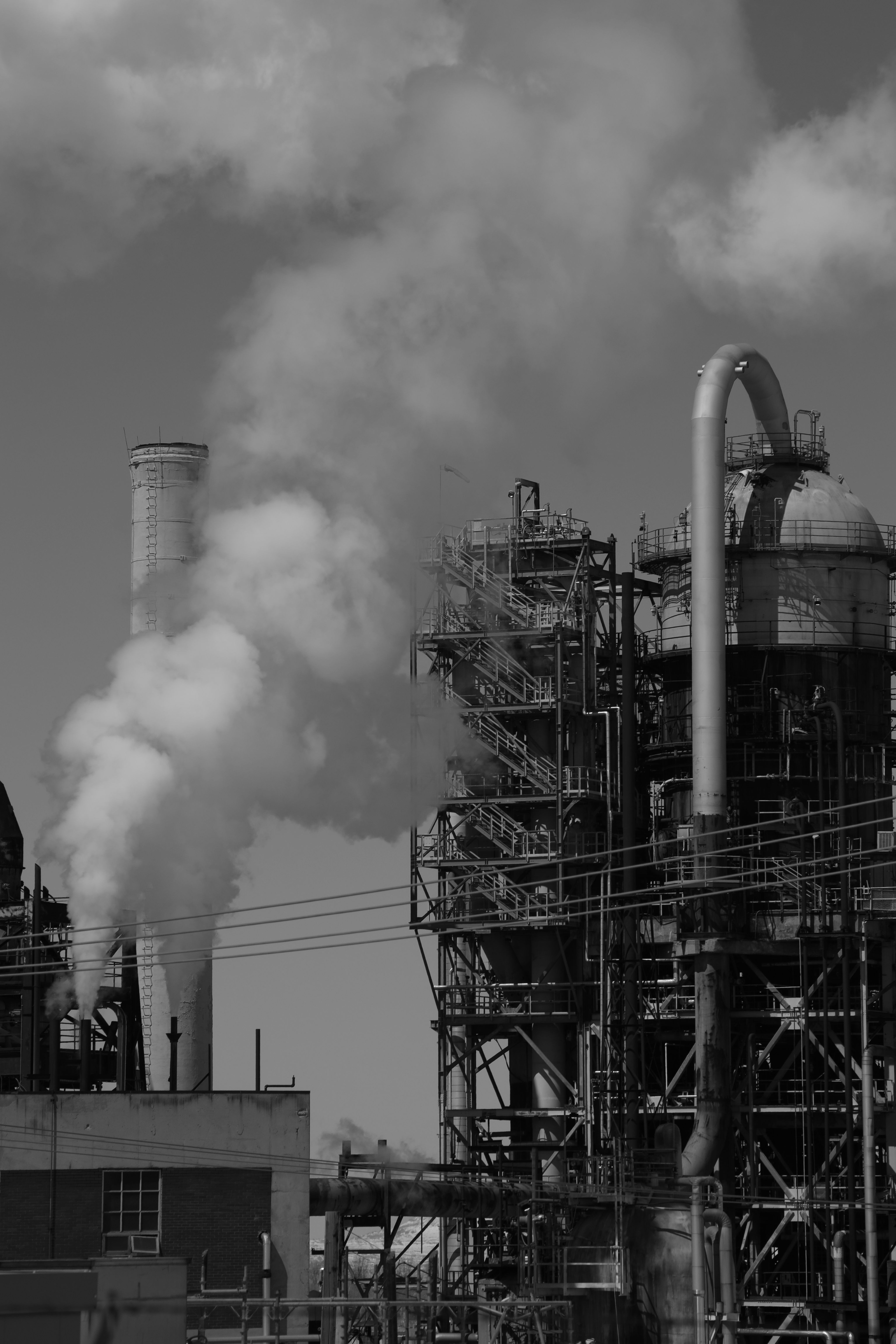 a black and white photo of smoke billowing from a factory